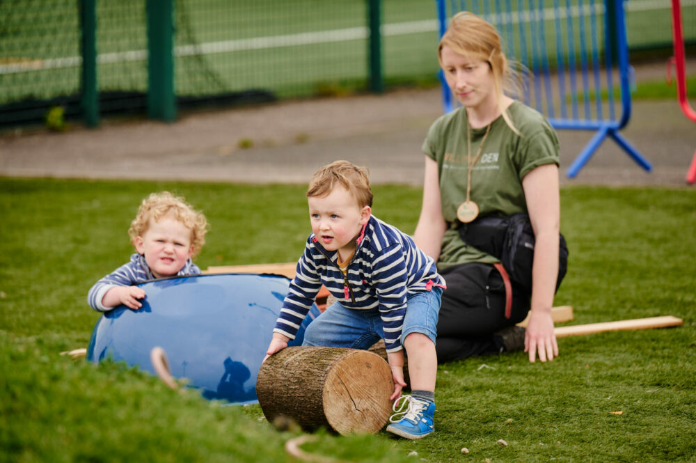 kids playing on the grass with logs and sticks