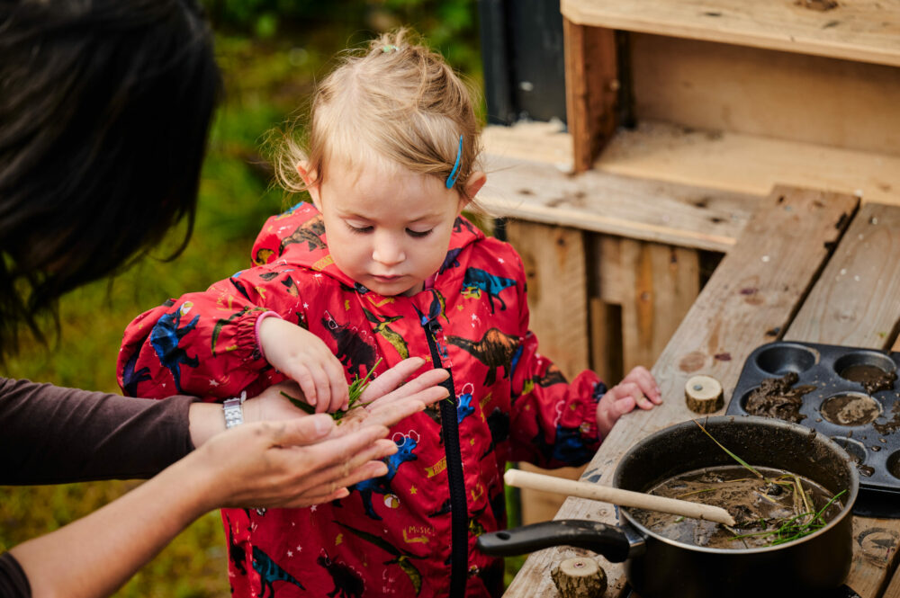 little girl plays in a mud kitchen
